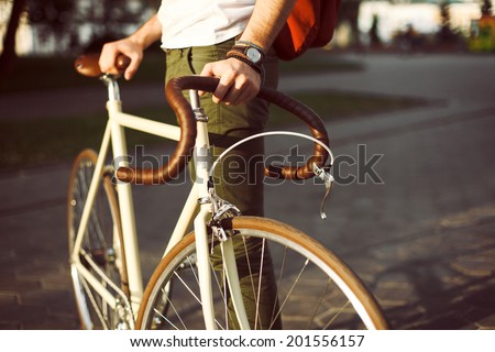 Young hipster style man posing with bicycle on the street sport style picture handsome guy with red backpack ready for trip