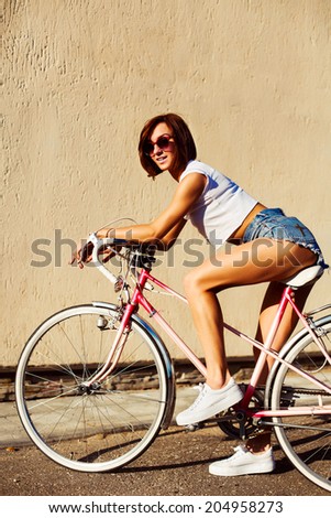 Pretty young sexy hot sport style woman posing in summer hot weather on the street riding vintage bicycle and have fun alone