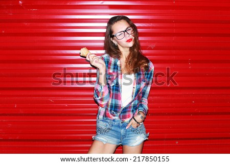 Outdoor colorful portrait of pretty young sexy woman posing and having fun in the night eating ice-cream with her nice red lips on urban style background
