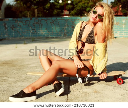 Pretty young sexy sensual tanned sport woman in bikini sitting on longboard in summer hot time lifestyle outdoor fashion portrait