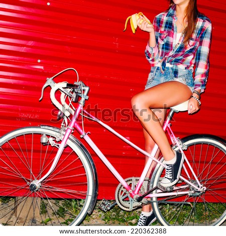 Outdoor night fashion colorful portrait of pretty young sexy woman with banana and retro vintage pink bicycle