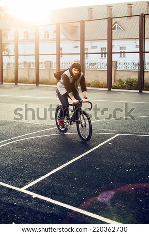 Hipster style handsome man riding fixed gear bicycle in autumn in city urban style background