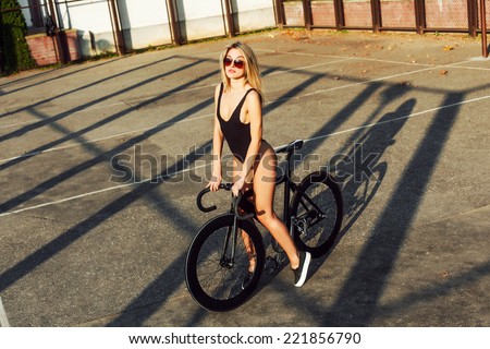 Outdoor fashion photo of young tanned sexy sport style woman posing on the playground with fixed gear trek bicycle
