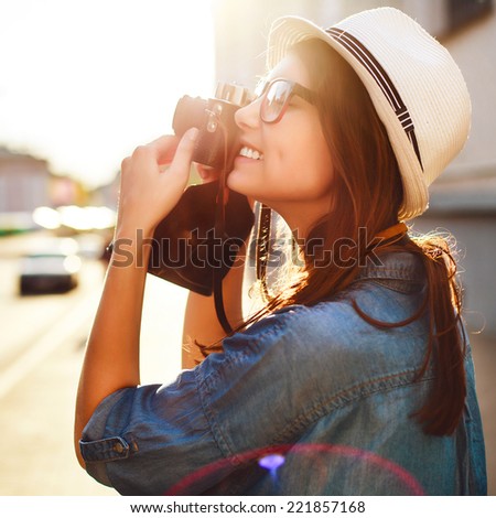 Outdoor summer fashion sensual portrait of pretty young beautiful brunette woman hipster photographer tourist taking pictures in old city in summer evening and smiling