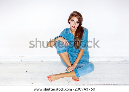 Pretty young sexy fashion sensual woman posing on white wall background dressed in hipster style jeans outfit