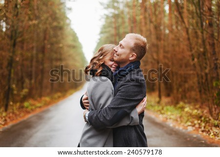 Outdoor closeup portrait of pretty young couple in love having fun in cold weather and feeling happy together on the forest road