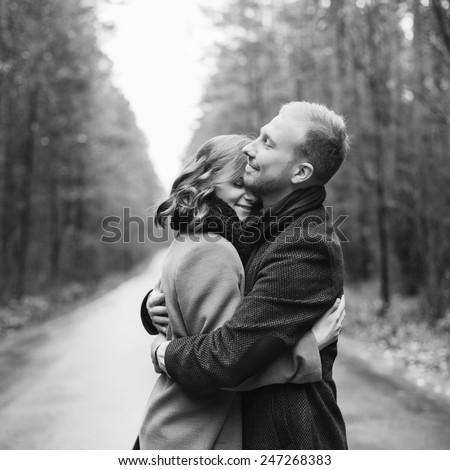 Outdoor vintage black and white fashion portrait of pretty young hipster couple in love posing in forest