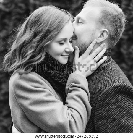 Black and white photo of pretty young couple posing outdoor in cold spring weather having fun together in love and happiness