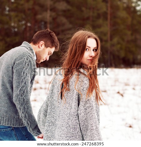 Closeup portrait of pretty young beautiful couple in love walking together on snow cold forest field