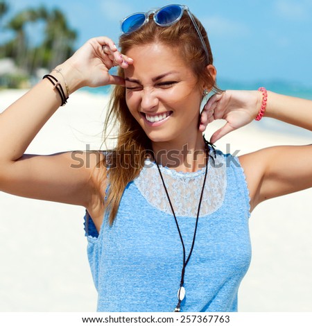 Pretty young beautiful sensual blonde woman posing on the beach and have fun alone near blue sea and sky smiling happy face closeup portrait