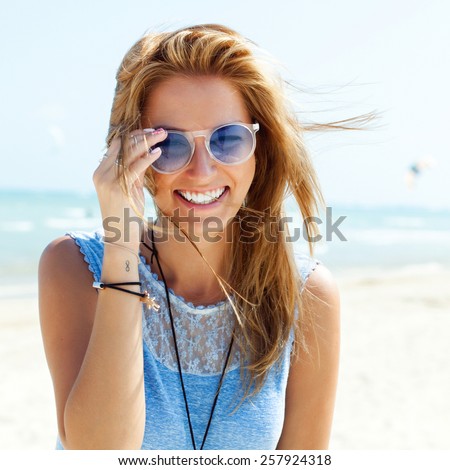 Outdoor fashion portrait summer beach style of young beautiful blonde woman fresh face smiling on the beach of tropic island having fun on vacation in blue dress and sunglasses