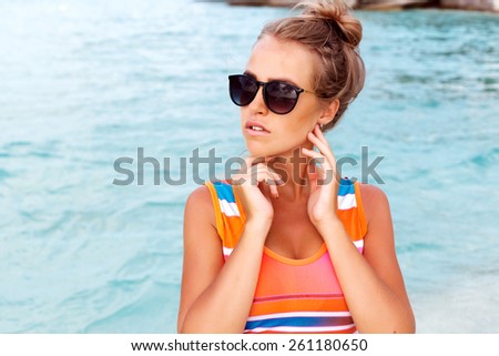 Pretty young fashion outdoor summer closeup portrait of young pretty blonde sexy tanned woman having fun on the beach on tropic island near blue water in sunglasses tourist style relax