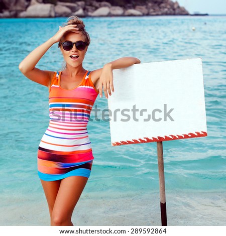 Pretty blonde smiling happy surprised woman in red dress posing on blue sea background