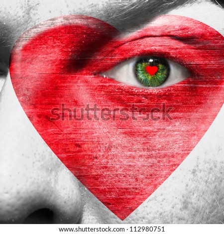 Red heart painted on white face with heart shaped red pupil in a green eye