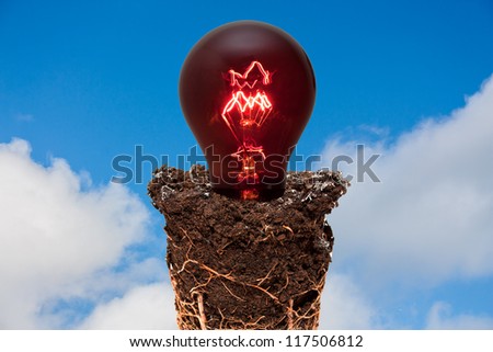 Earth and red light bulb against blue cloudy sky