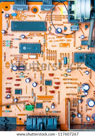 Vintage orange populated printed circuit board PCB showing the conductive traces vias the through-hole paths to the other surface and some mounted electrical components