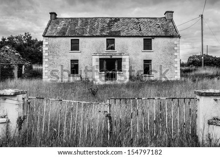 Spooky abandoned house with a locked gate in black and white