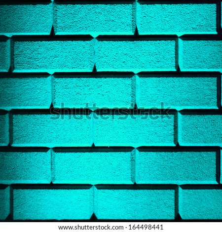 Brick wall made with big bricks lit up with cyan lighting in square format frame