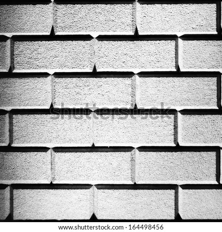 Brick wall made with big bricks lit up with white lighting in square format frame
