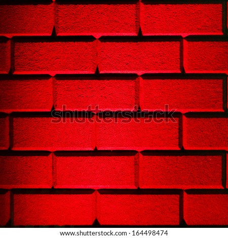 Brick wall made with big bricks lit up with red lighting in square format frame