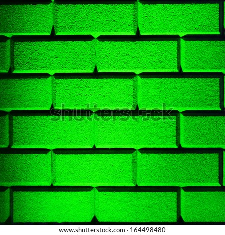 Brick wall made with big bricks lit up with green lighting in square format frame