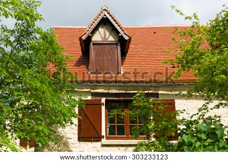 Dormer window located on the red clay roof of a French country house
