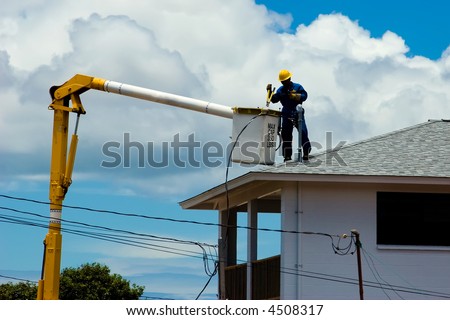 Electric Company repairman on top of a house hooking up the power cables