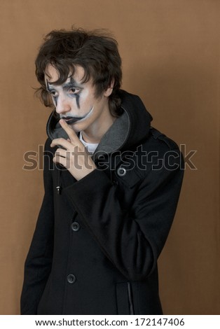 a young man  with  make  up , as a sad clown in black clothes
