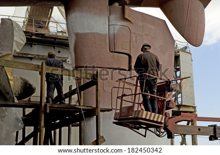 Unidentified men, the brigade painters paint the hull in dry dock city of Vladivostok