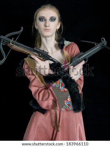 Young girl with a crossbow in the original dress on black  background