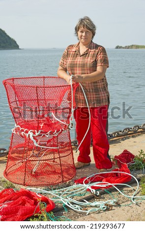 Woman  on the shore of the port village of Transfiguration, Primorye, Russia, making traps for shrimp