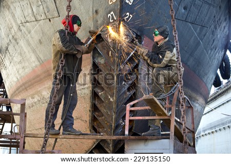 Welders on black metal, repairing a ship in dry dock