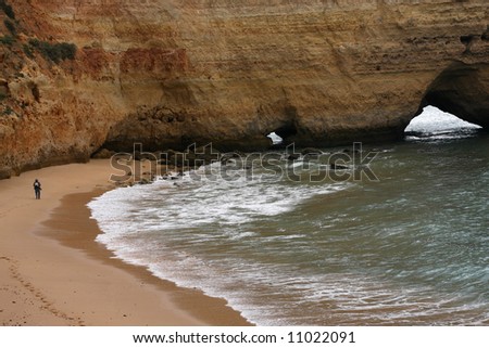 Isolated beach in Algarve (south of Portugal); man walking on the sand;