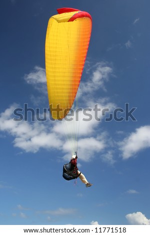 A woman in a yellow/red paraglider above the ocean (Reunion Island/Indic Ocean).
