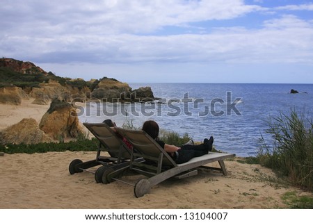 A couple laying in two wooden sun beds on the top of the cliff.