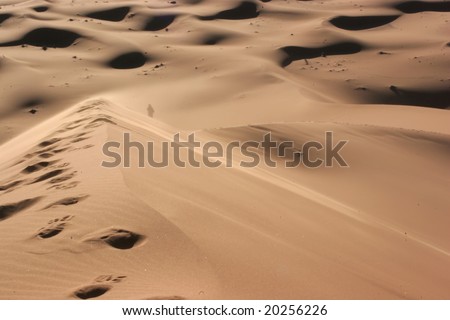 Silhouette of a person walking alone in the desert;