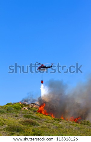 emergency helicopter extinguishes flames of a raging bush fire