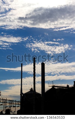 silhouette of a industrial factory against a blue sky