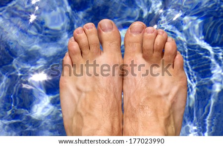 ariel view of mans feet as he is about to dive into a clear blue swimming pool