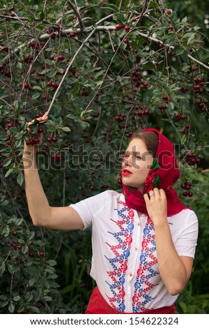 Young Russian woman in traditional folk dress in summer garden. Russia travel background.