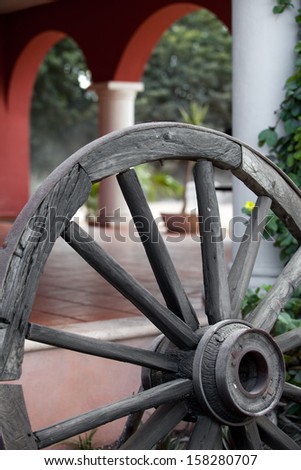 Old vintage wooden wheel by a country house.