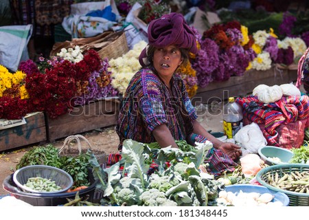 Middle-aged indigenous woman sells vegetables and flowers at traditional weekly market in Chichicastenango (Chichi), Guatemala.