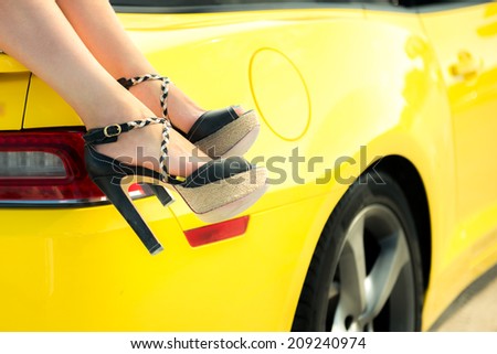Luxury car travel concept background. Woman feet on luxury car.