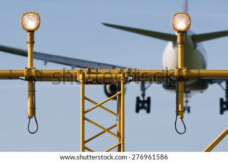 Passenger plane is decending towards the runway behind the runway light.