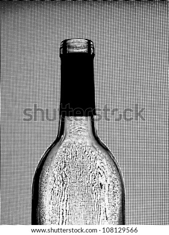 Abstract black and white background design made from an empty  wine bottle against a wire window screen.