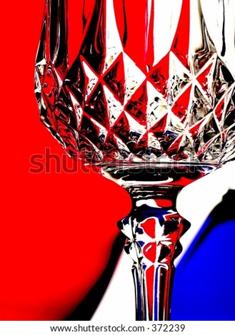 Wine glass in front of red and blue transparent glassware.