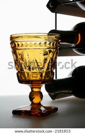 Wine glass, bottles and wine rack on white background.