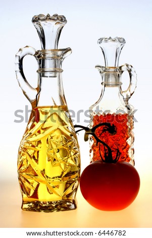 Oil and vinegar bottles with a tomato on a blue and yellow background.