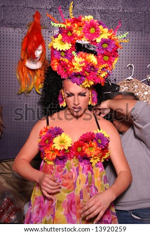 Drag queen having her dress done up by an un-identifiable man before a show.