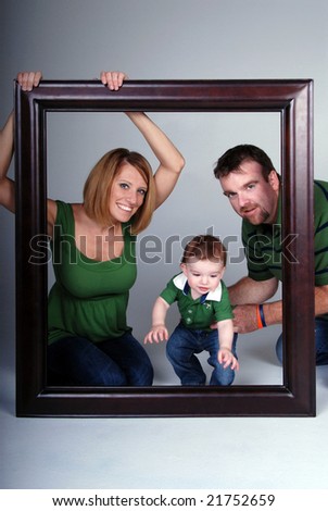 Portrait of a family looking through a large wooden frame.